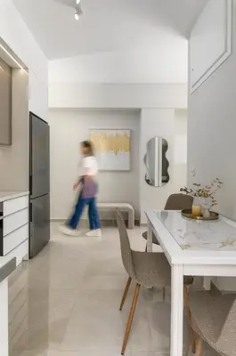 a woman walking through a kitchen with a table and chairs at SugarDustApt Elegant Retreat 150m from the Sea in Chania Town