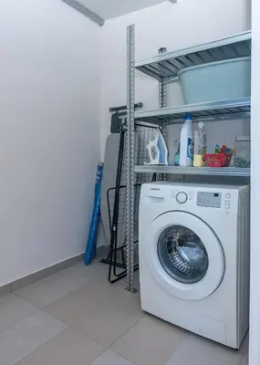 a washing machine in a laundry room with a shelf at Murelos in Chania Town