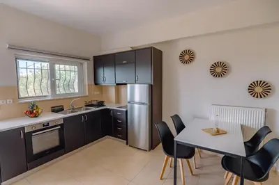 a kitchen with black cabinets and a table with chairs at Ibis Apartments Chania,close to the beach in Chania Town