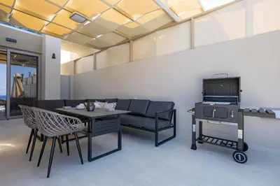 a living room with a table and a grill at Theo Luxury Villas With Sea View in Agia Marina Nea Kydonias
