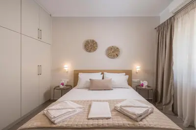 a white bedroom with a large bed with two tables at Eranthis Apartment in Chania Town