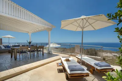 a patio with a table and chairs and an umbrella at Villa Alia in Sfakiá