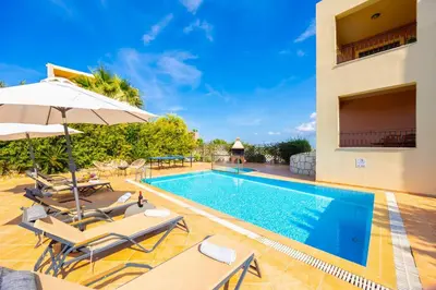 a villa with a swimming pool with chairs and an umbrella at Villa Pasiphae 1 in Stalos