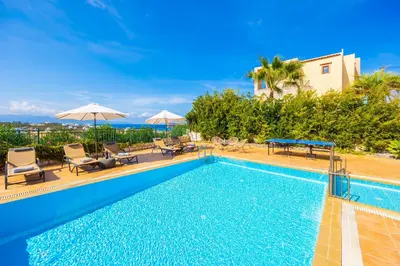 a swimming pool with chairs and umbrellas next to at Villa Pasiphae 1 in Stalos