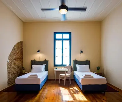 two beds in a room with a desk and a window at Sundial Lodge in Chania Town