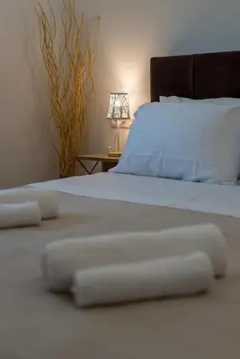 a bedroom with a bed with white sheets and a lamp at Casa Manou - Kalyves beach in Kalyves
