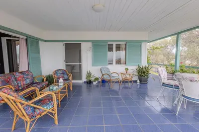 a porch with chairs and a table and chairs at Rastoni - Beach Family House in Chorafakia