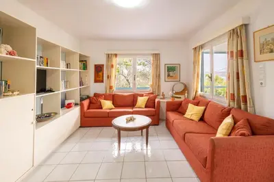a living room with two orange couches and a table at Rastoni - Beach Family House in Chorafakia