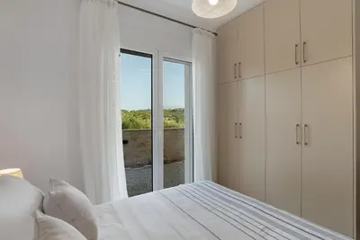 a white bedroom with a bed and a large window at Villa Terra Nuova in Kalyves