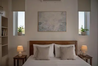 a bedroom with a bed with pillows and two windows at Villa Terra Nuova in Kalyves