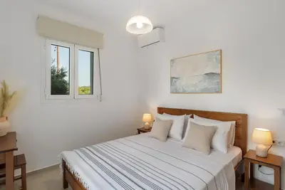 a white bedroom with a bed and two windows at Villa Terra Nuova in Kalyves