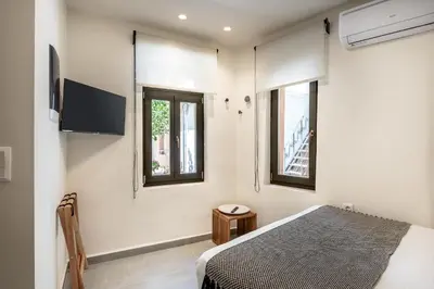 a bedroom with a bed and two windows at Amarillide rooms in Chania Town