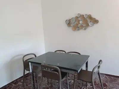 a dining room table with chairs and a clock on the wall at Charming Apartment In The Heart Of The City Chania in Chania Town