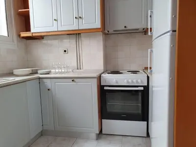 a kitchen with white cabinets and a stove and refrigerator at Charming Apartment In The Heart Of The City Chania in Chania Town