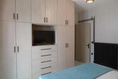 a bedroom with white cabinets and a tv and a bed at Dedalos City Apartment in Chania Town