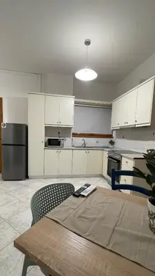 a kitchen with white cabinets and a table and a refrigerator at Murele apartments in Daratso