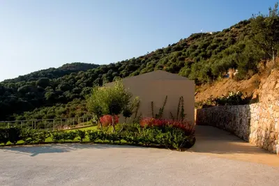 a building in front of a mountain with trees at Aksos Suites Accessible Accommodation in Ayiá
