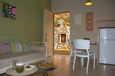 a living room with a couch and a kitchen with a fireplace at Aksos Suites Accessible Accommodation in Ayiá