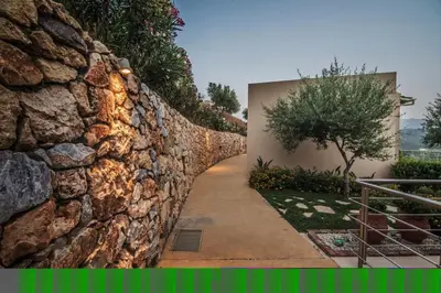 a stone wall next to a walkway at Aksos Suites Accessible Accommodation in Ayiá