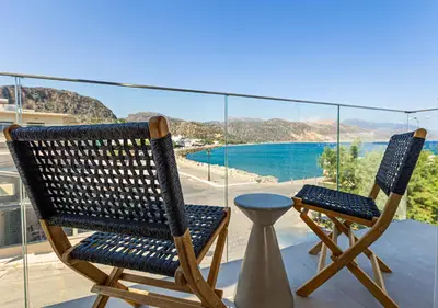 two chairs on a balcony with a view of the water at Aurora By Anasa in Palaiochóra