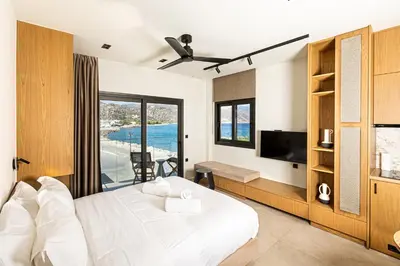 a bedroom with a white bed and a balcony at Aurora By Anasa in Palaiochóra