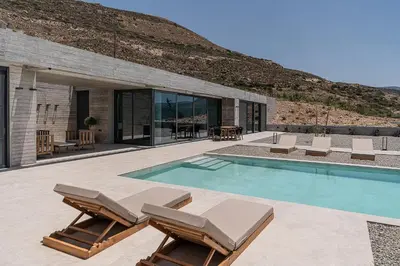 a swimming pool with lounge chairs and a house at Alba Cave Villas in Chania Town