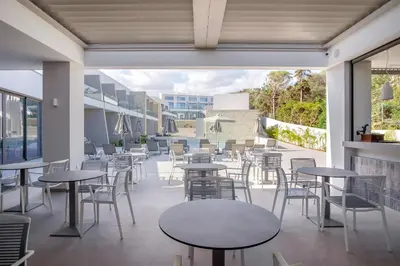 an empty restaurant with tables and chairs and windows at Phos Hotel Adults Only in Plataniás