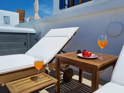 two glasses of wine and a table on a balcony at All Season Lovely Seafront Cottage in Kissamos