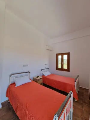 a bedroom with two beds with red sheets and a window at All Season Lovely Seafront Cottage in Kissamos