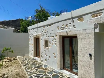 a facade of a white building with rocks on it at Stone Luxury Suite in Galatás