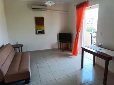 a living room with a couch and a tv and a window at Despoina's Sea View Apartment in Chania Town