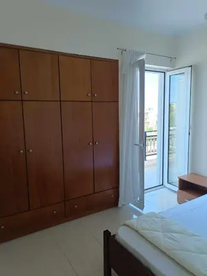 a bedroom with a bed and wooden cabinets and a balcony at Despoina's Sea View Apartment in Chania Town