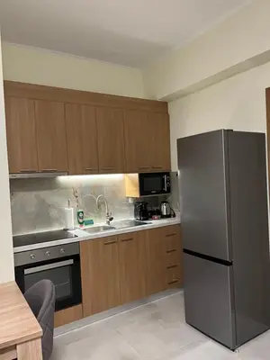 a kitchen with a stainless steel refrigerator and wooden cabinets at GREENHOUSE maleme in Ayiá
