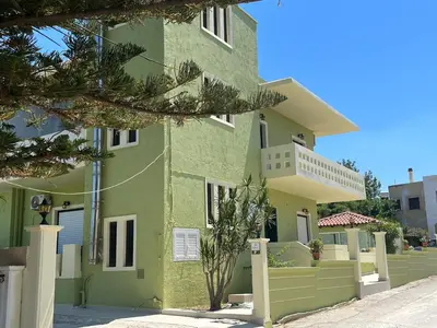 a green building with a fence in front of it at GREENHOUSE maleme in Ayiá