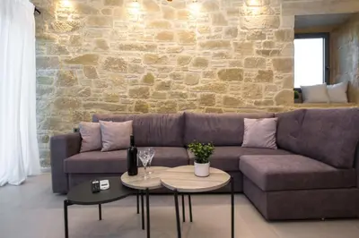 a living room with a couch and a stone wall at Basiliko in Kalidhónia