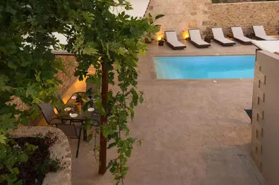 a patio with a table and chairs next to a pool at Basiliko in Kalidhónia