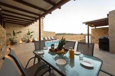 a glass table with a bowl of fruit on a patio at Basiliko in Kalidhónia
