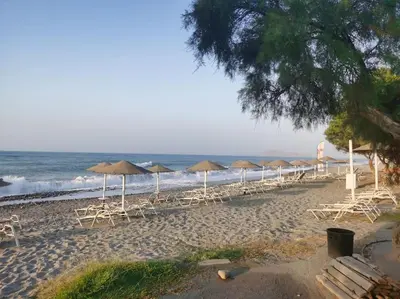 a beach with chairs and umbrellas and the ocean at \u4e24\u5367\u5ba4\u516c\u5bd3-\u5e26\u9732\u53f0\u82b1\u56ed in Chania Town