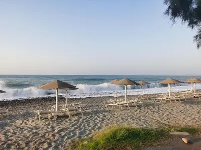 a group of chairs and umbrellas on a beach at \u4e24\u5367\u5ba4\u516c\u5bd3-\u5e26\u9732\u53f0\u82b1\u56ed in Chania Town