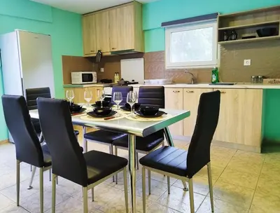 a kitchen with a table and chairs with wine glasses at SleepiLi in Vrísai