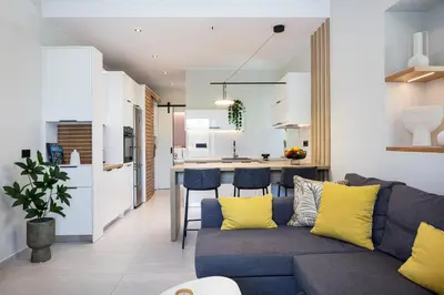 a living room and kitchen with a blue couch and yellow pillows at Centrale Apartment Chania in Chania Town