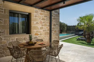 a patio with a table and chairs and a pool at Semes luxury villas in Drapaniás