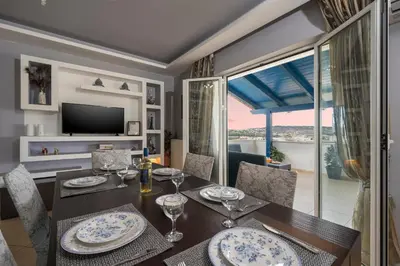 a dining room with a table and chairs and a television at Maison Evelyn in Tsikalariá