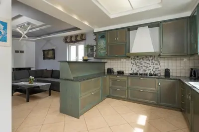 a kitchen with green cabinets and a living room at Maison Evelyn in Tsikalariá