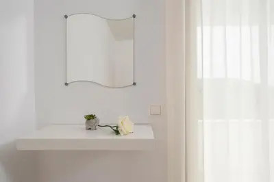 a white bathroom with a sink and a mirror at Maison Evelyn in Tsikalariá