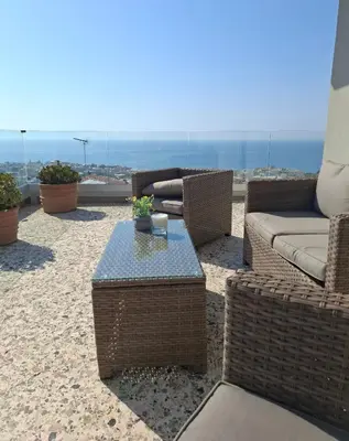 a patio with wicker chairs and a table and the ocean at UPapartment in Chania Town