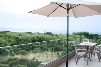 a balcony with an umbrella and a table and chairs at Welcome U in Gerani Chanion