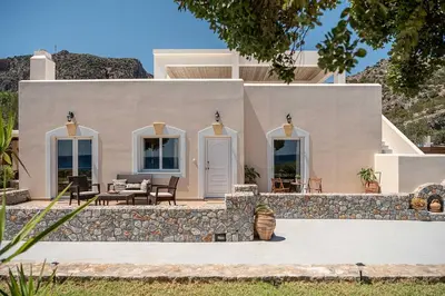 a white house with a stone retaining wall at Casa Horizon in Palaiochóra