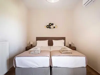 a bedroom with two beds with white sheets and a clock on the wall at Casa Horizon in Palaiochóra