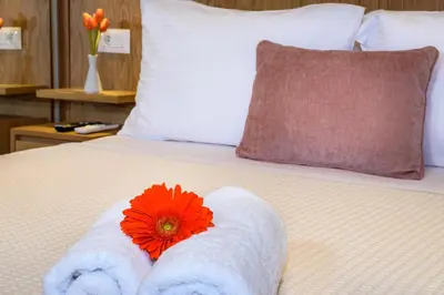 a red flower sitting on top of a bed with towels at Nicolas Urban Luxury Living in Souda